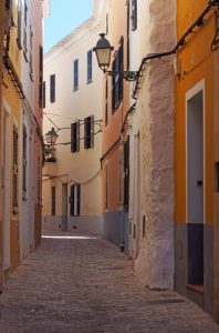 28647781-an-empty-picturesque-narrow-alley-of-old-painted-houses-and-street-lamps-in-ciutadella-menorca