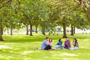 Group,Of,Young,College,Students,Sitting,On,Grass,In,The